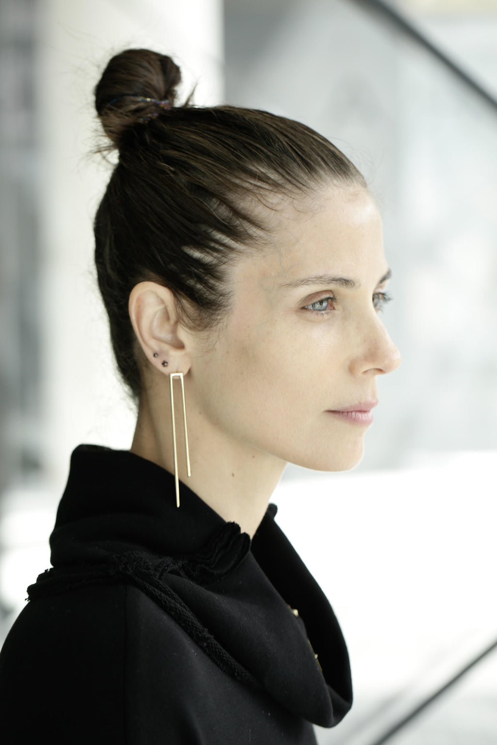 Model wearing Noritamy Open Rectangle Earrings in gold — elongated minimalist silhouette shown in profile view
